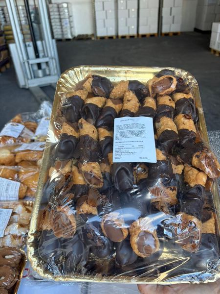 Vassoio di pasticcini, per lo più ricoperti di cioccolato, avvolti nella plastica, con un'etichetta con il prezzo. Ambiente industriale, potenziale panificio.