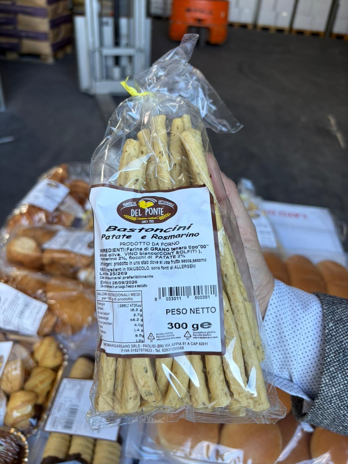 Una persona che tiene in mano un sacchetto di grissini con un'etichetta che recita