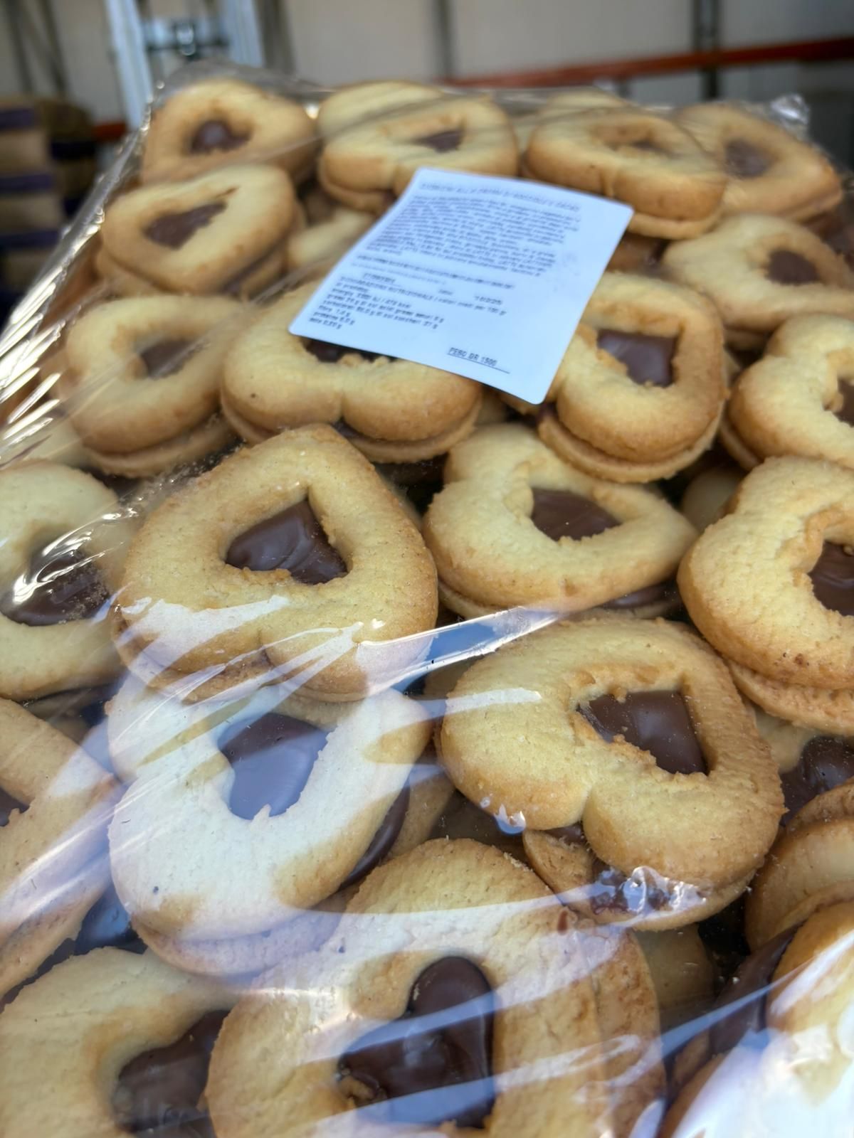 Biscotti a forma di cuore con cuore di cioccolato, avvolti in plastica trasparente.
