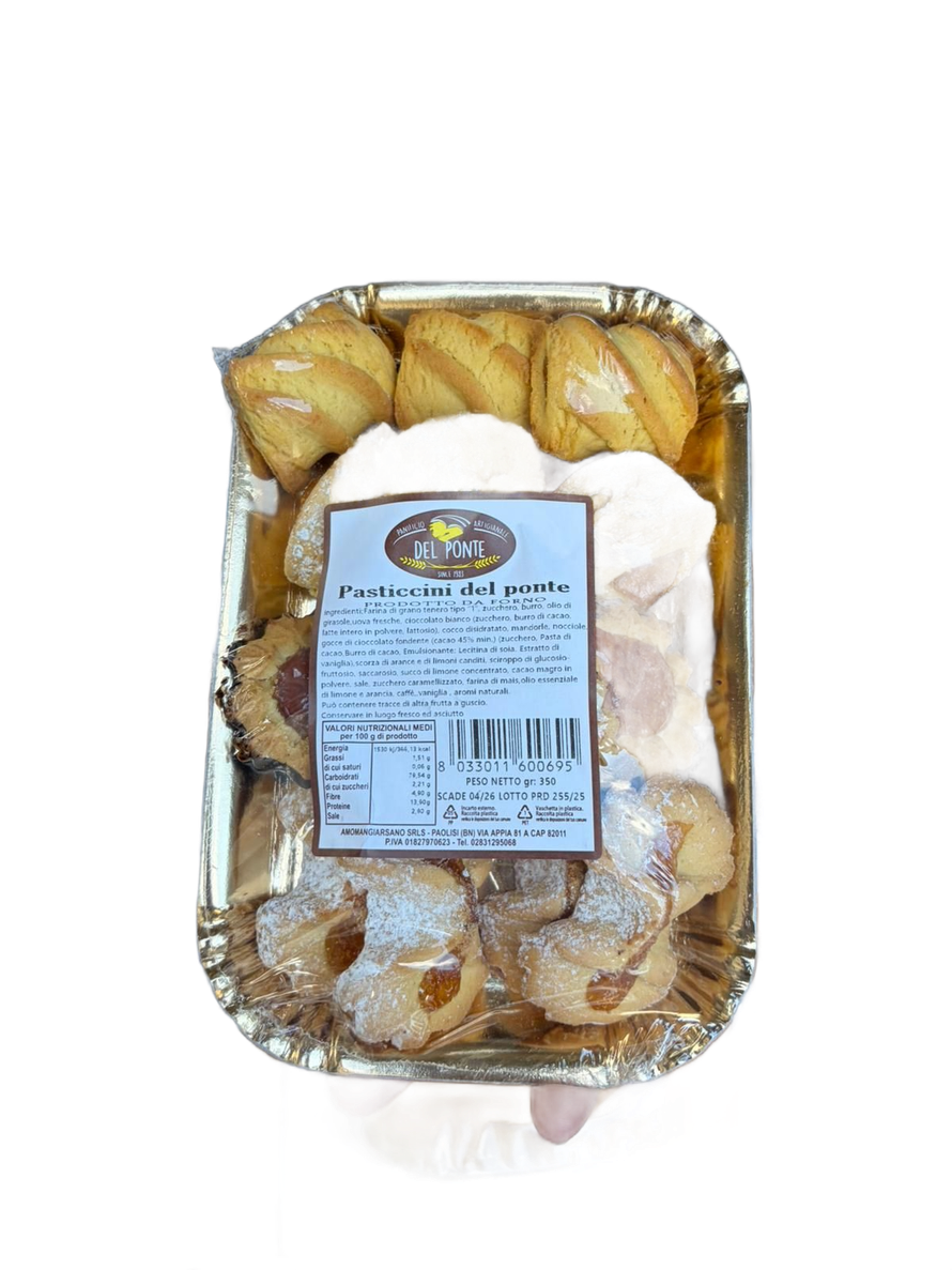 Vassoio di pasticcini assortiti, alcuni spolverati con zucchero a velo, in un vassoio rivestito di carta stagnola dorata.