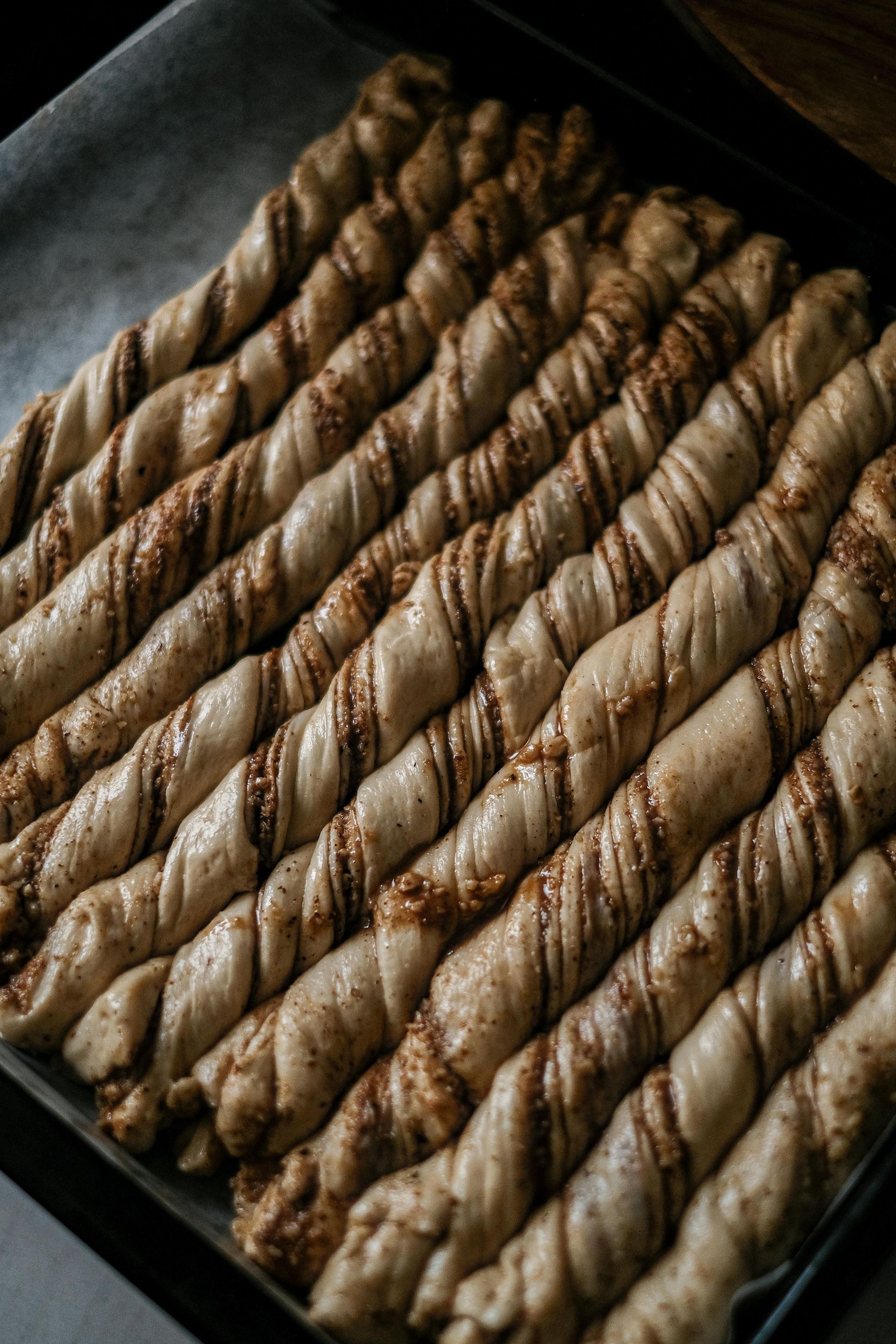 Una mano che regge un sacchetto trasparente di grissini, con l'etichetta del prodotto. Altri prodotti da forno sullo sfondo.