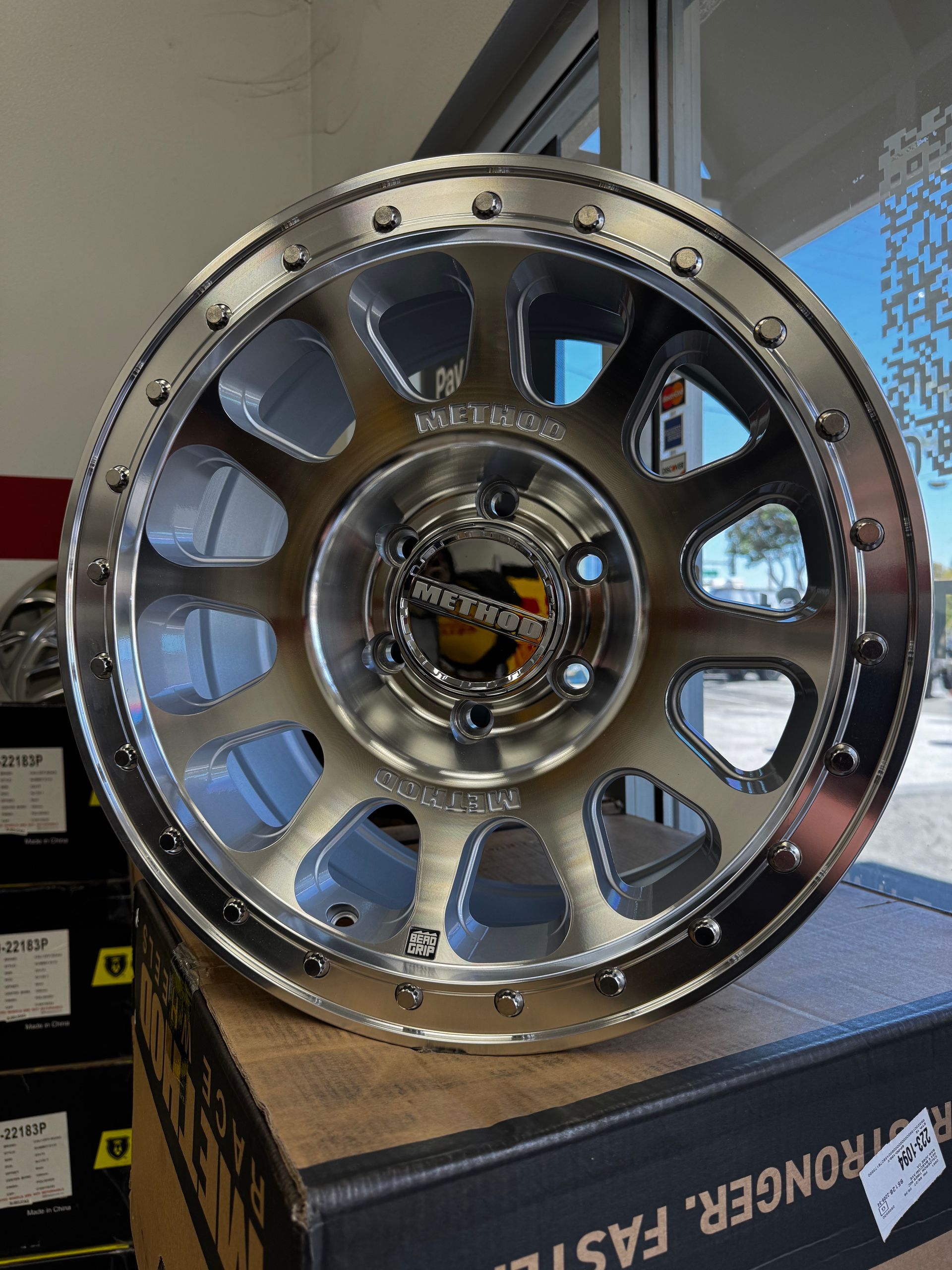 A machined aluminum wheel is sitting on top of a box that says stronger faster