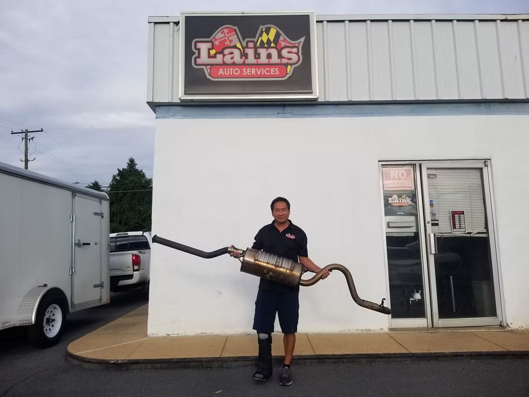 Man holding an exhaust system in front of 