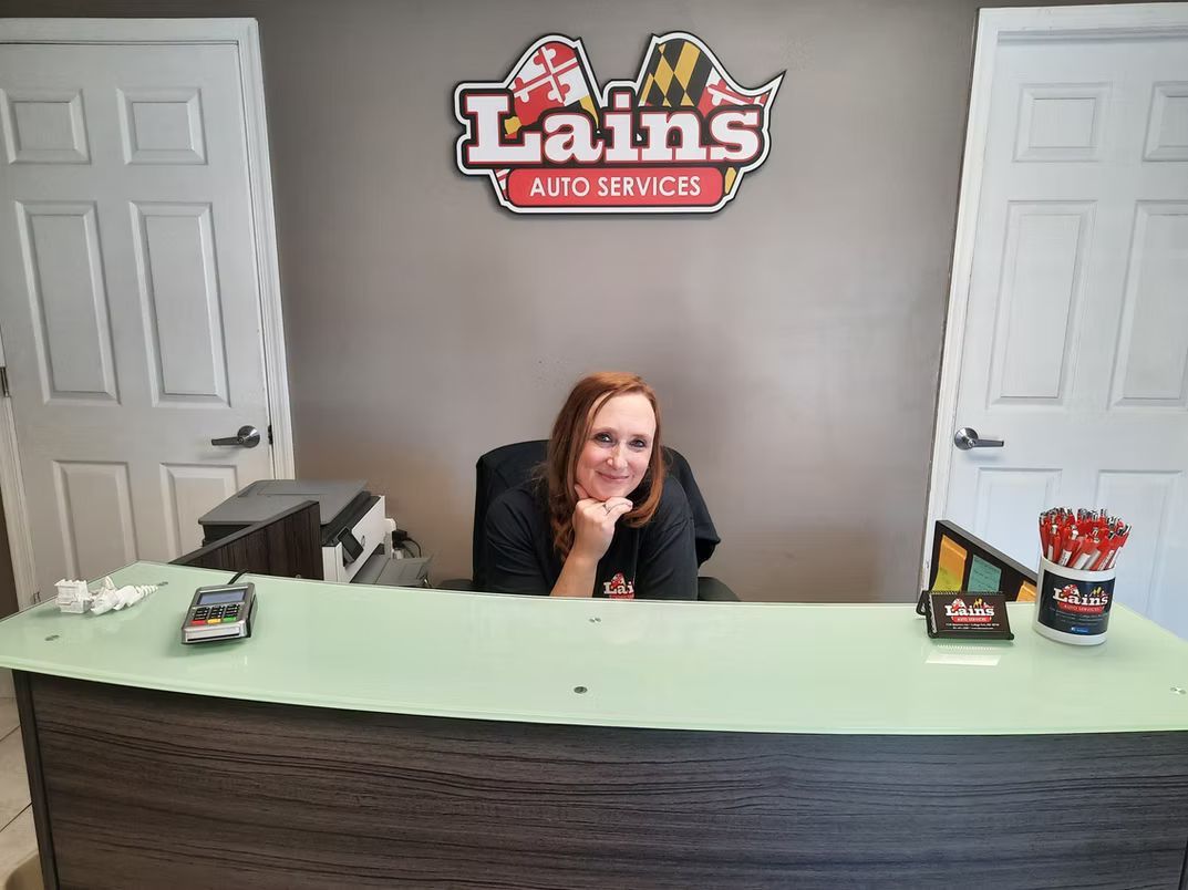Woman smiling behind a reception desk at Lains Auto Services. | Lains Auto Service