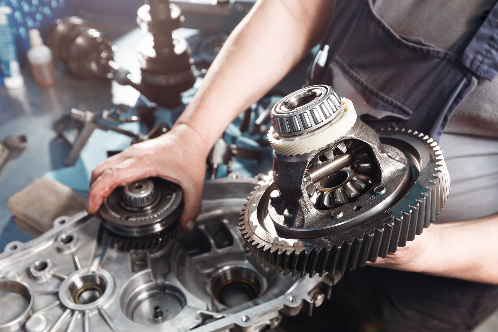 Mechanic holding car differential gear, working on vehicle parts in shop. | Lains Auto Services