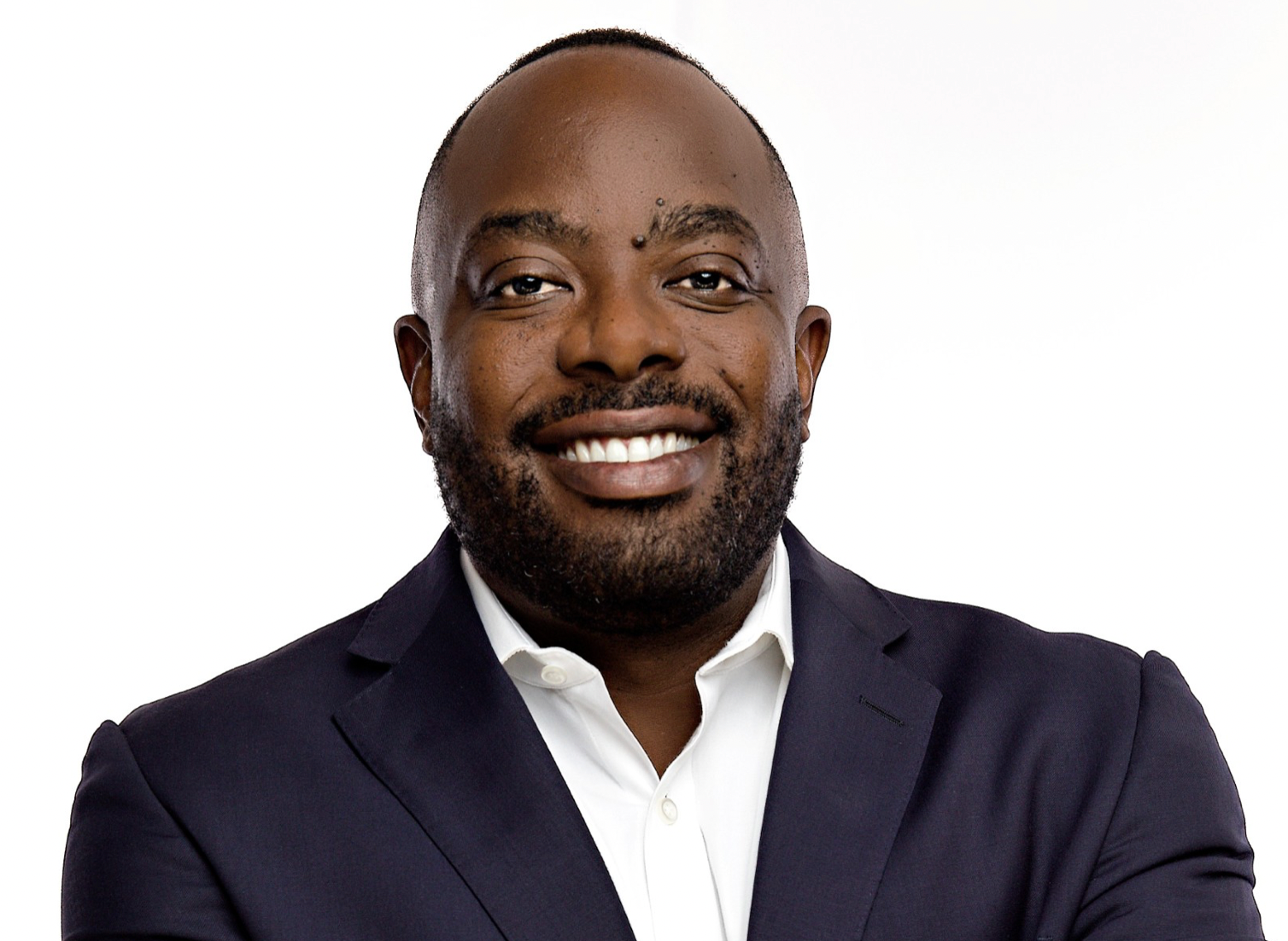 A man in a suit and white shirt is smiling for the camera.