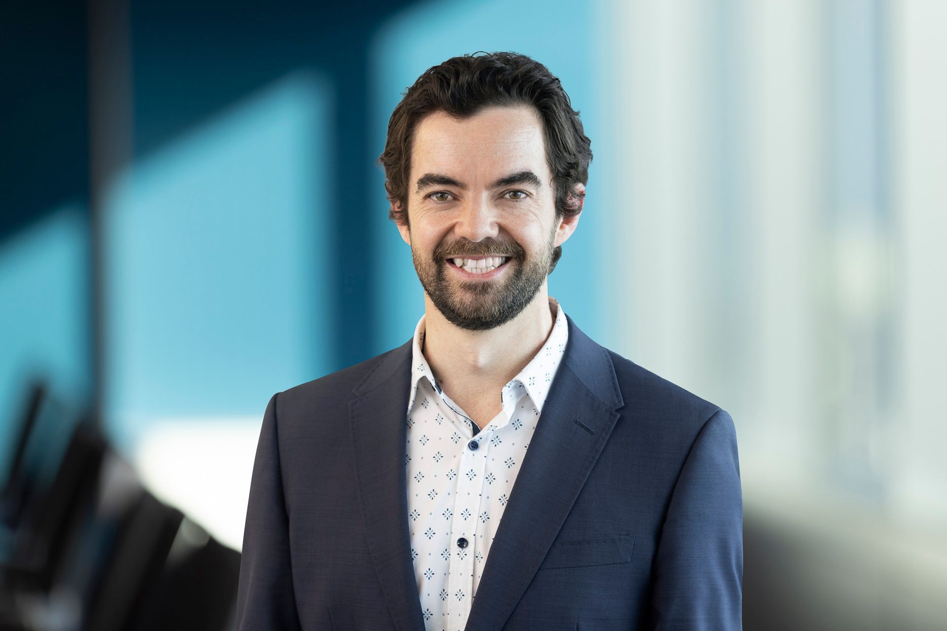 A man in a suit and white shirt is smiling for the camera.