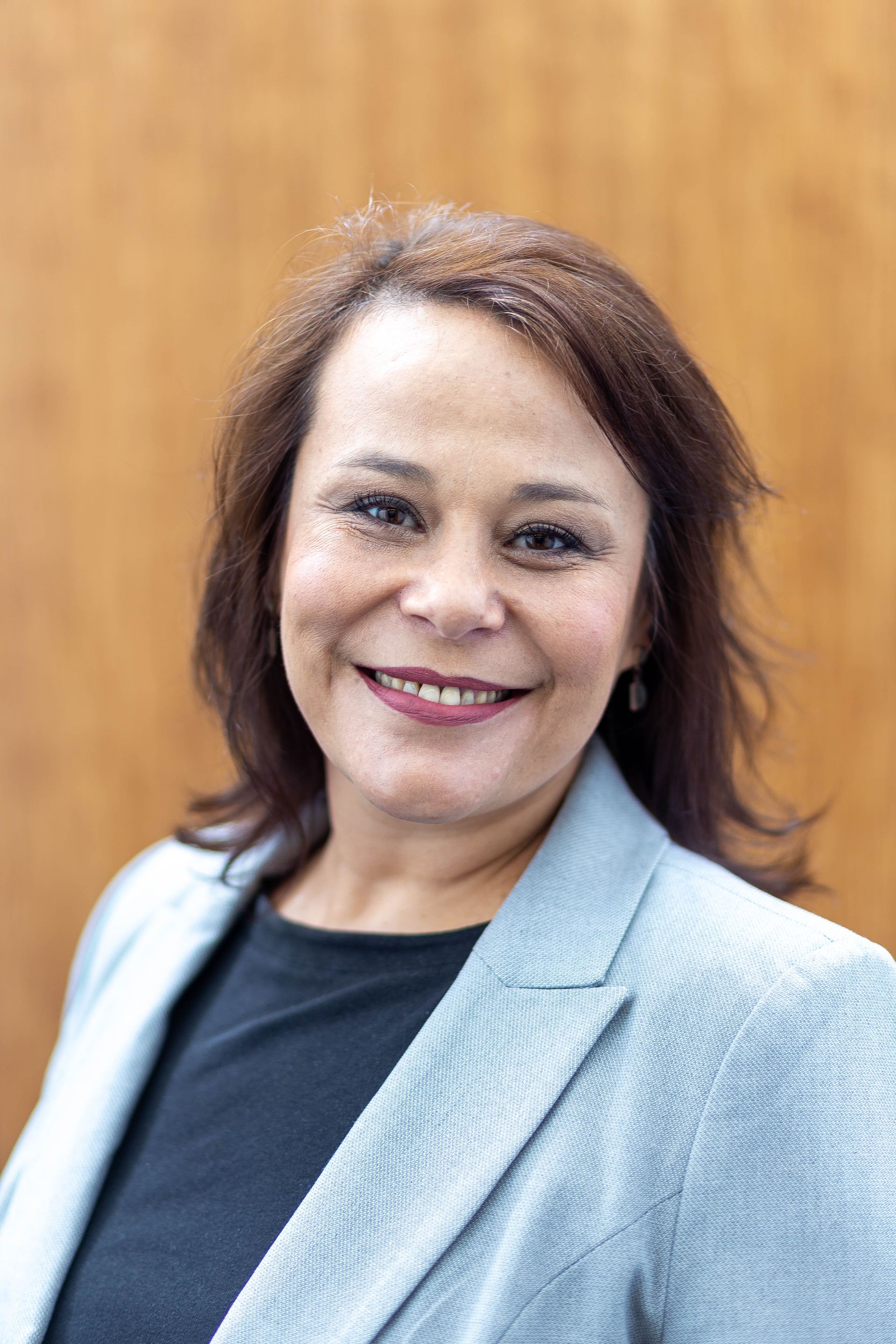 A man in a white shirt is standing with his arms crossed and smiling in a black and white photo.