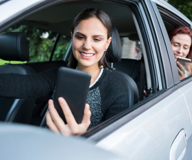A woman is sitting in a car looking at her phone
