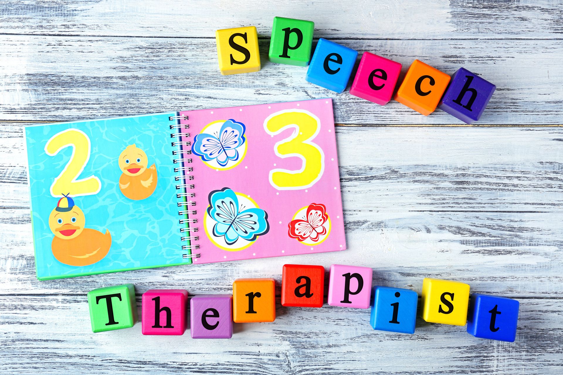 letter blocks that spell speech therapist and a children's book