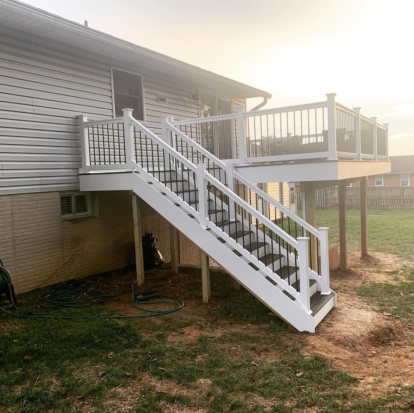 A white deck with stairs leading up to it and a house in the background.