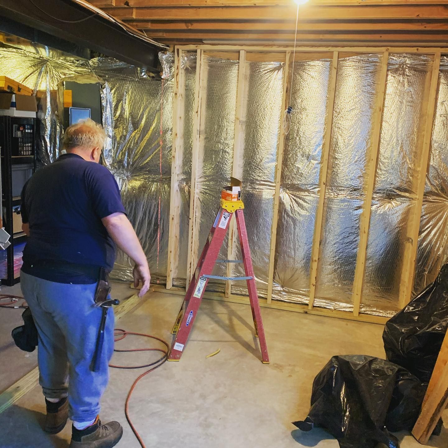 A man standing in a room with a ladder in front of him