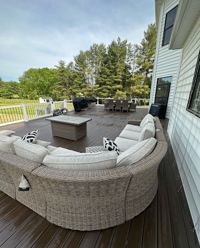 A large wicker couch is sitting on top of a wooden deck.
