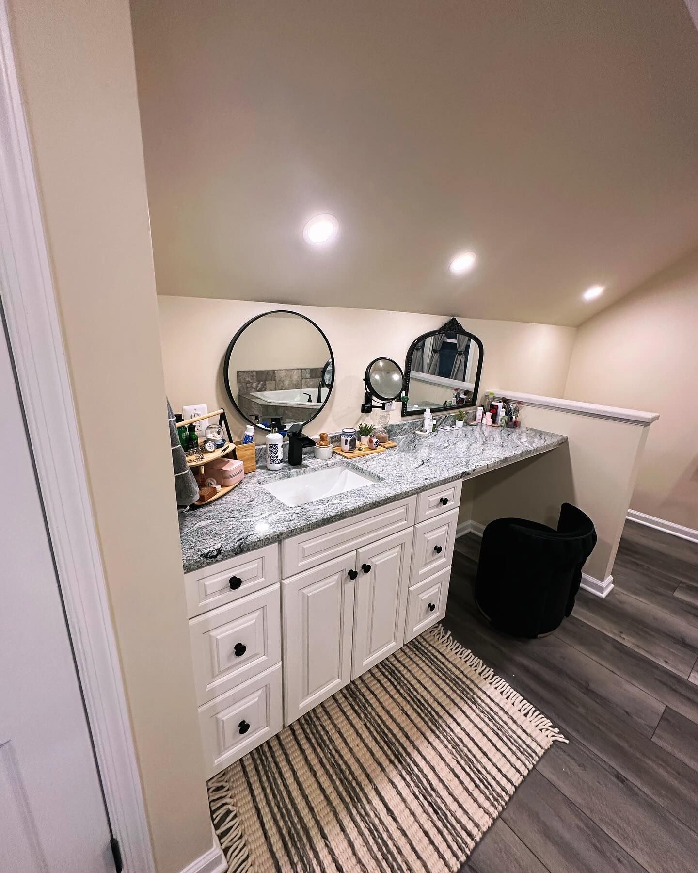 A bathroom with two sinks , two mirrors and a rug.