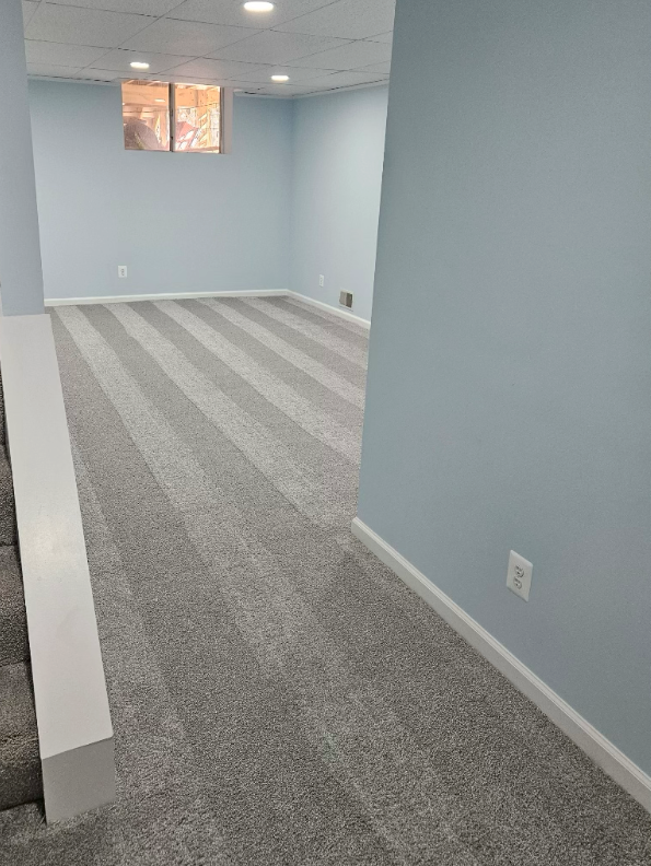 A basement with a striped carpet and blue walls.