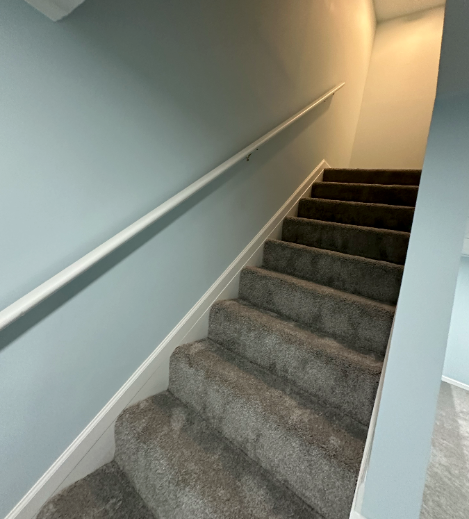 A set of carpeted stairs with a white railing