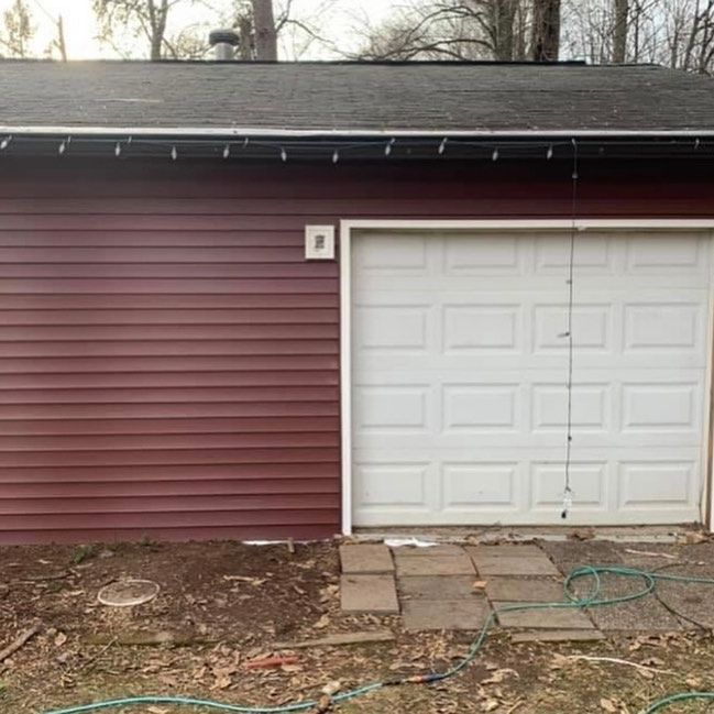 A garage with a red siding and a white garage door
