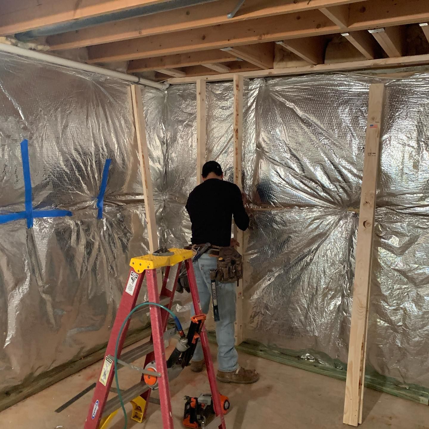 A man is working on a wall in a room with a ladder