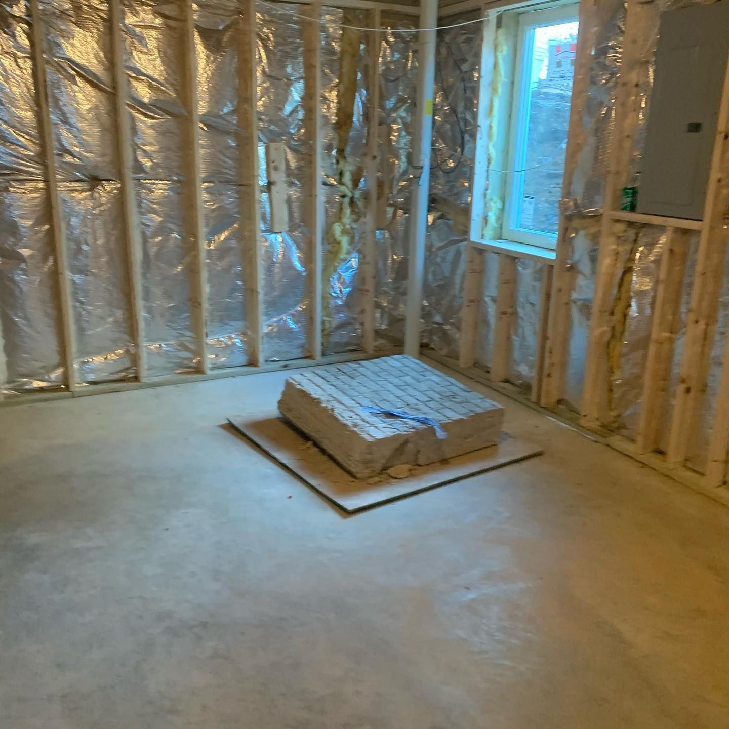 A room with a window and a piece of concrete on the floor