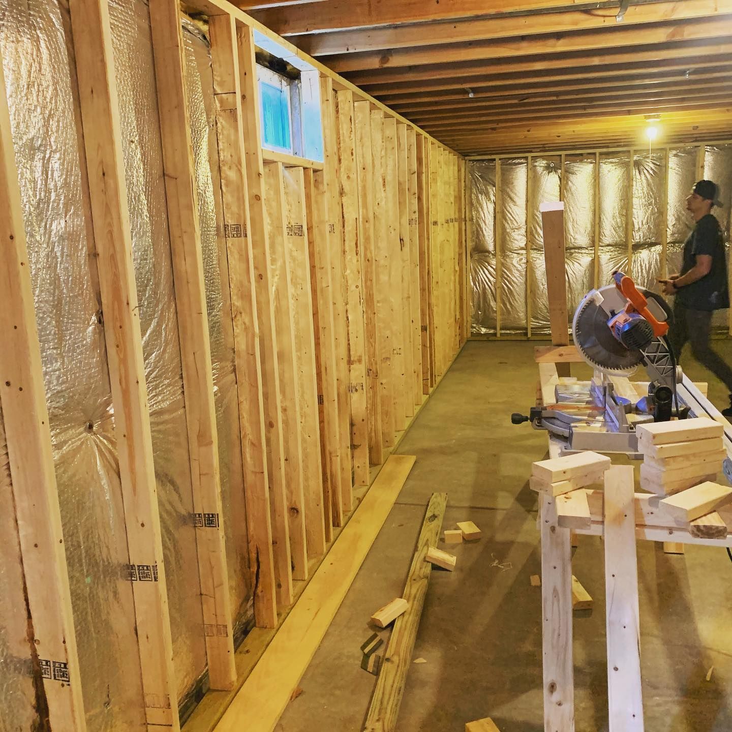 A man is cutting wood in a basement with a circular saw.