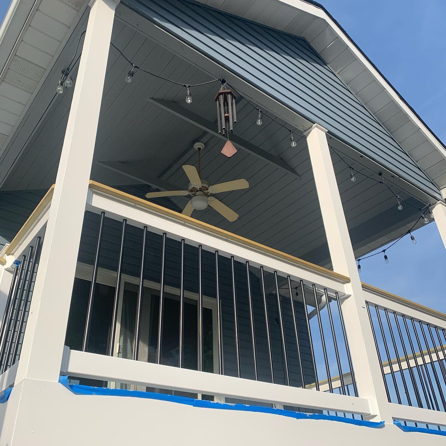A porch with a ceiling fan hanging from it