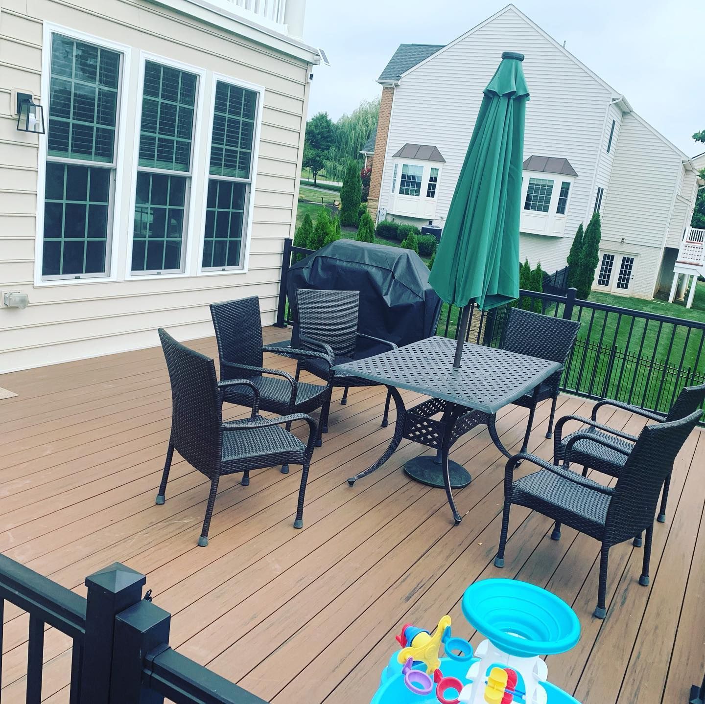 A deck with a table and chairs and a green umbrella