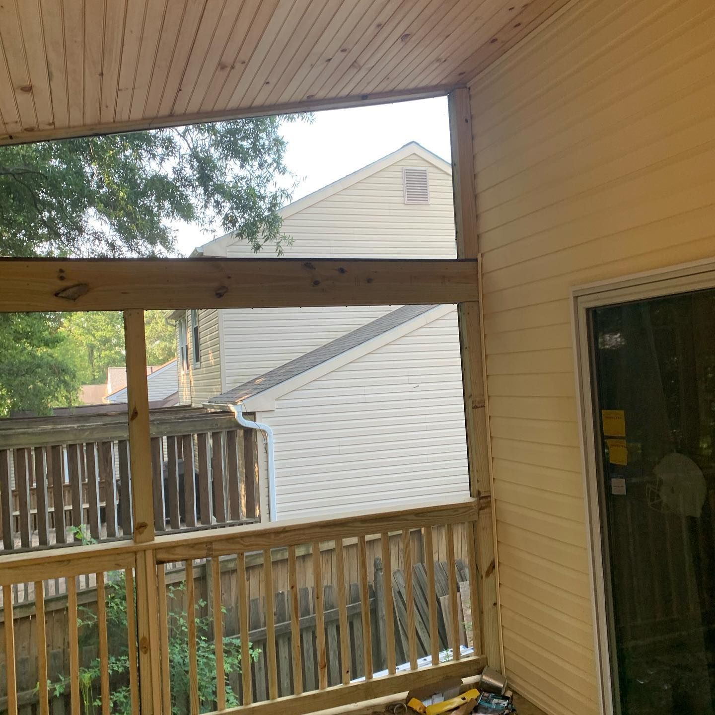 A porch with a sliding glass door and a wooden railing