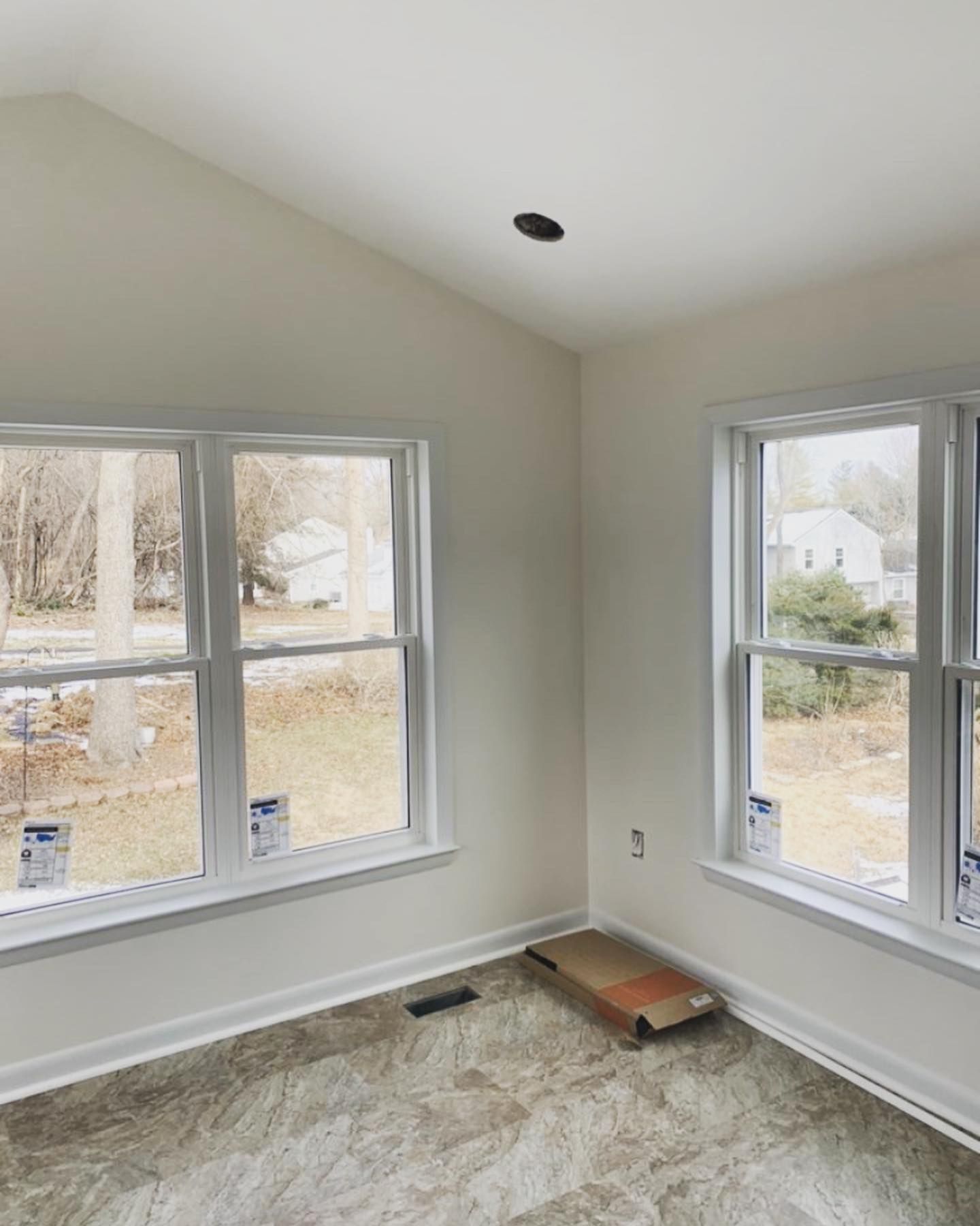 An empty room with two windows and a vaulted ceiling.
