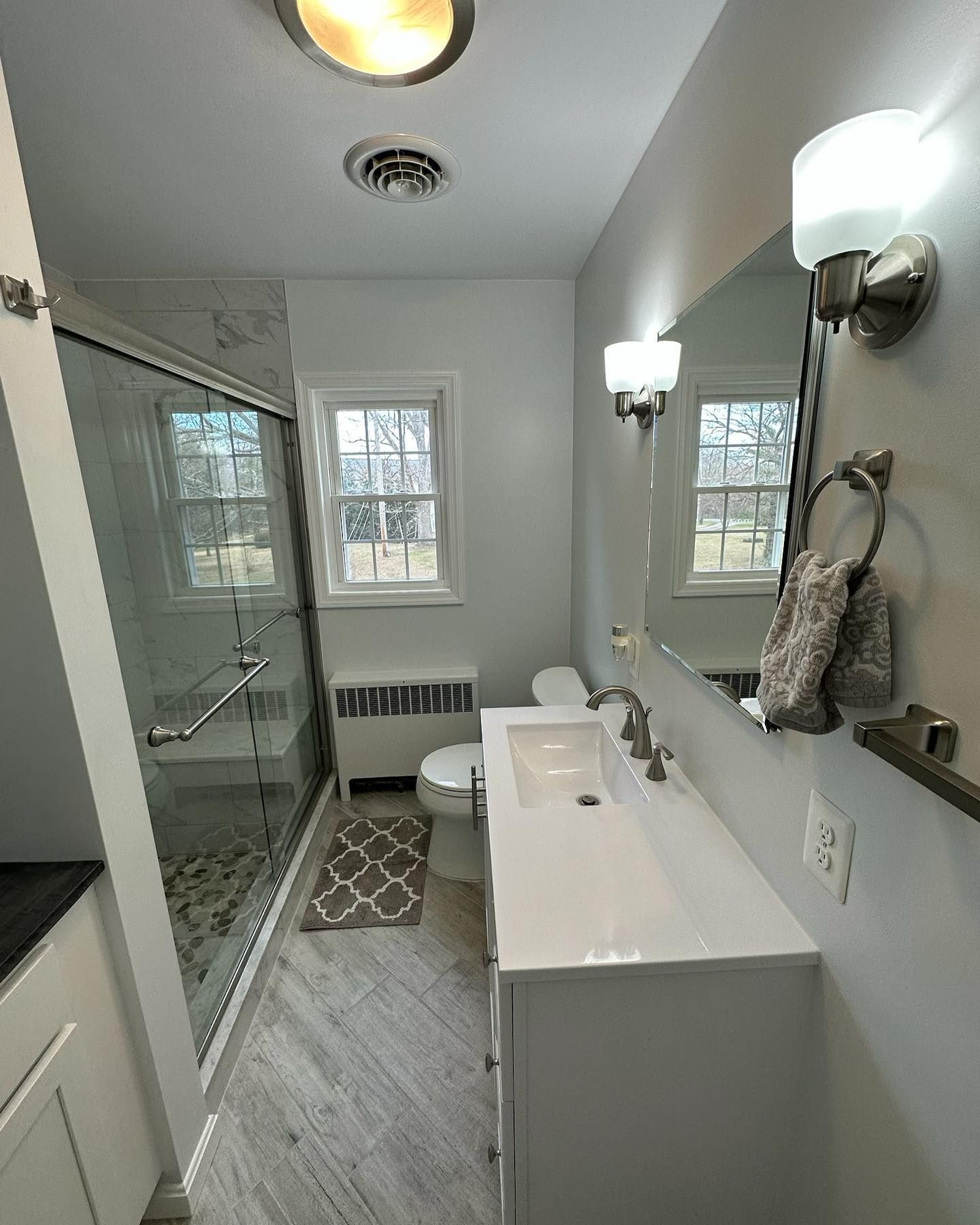 A bathroom with a sink , toilet , shower and mirror.