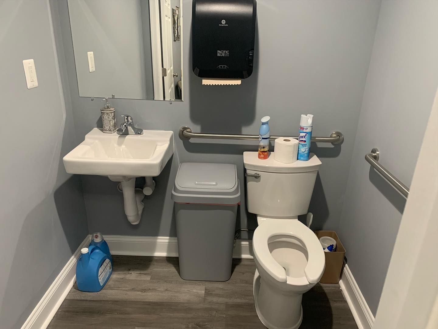 A bathroom with a toilet , sink and trash can