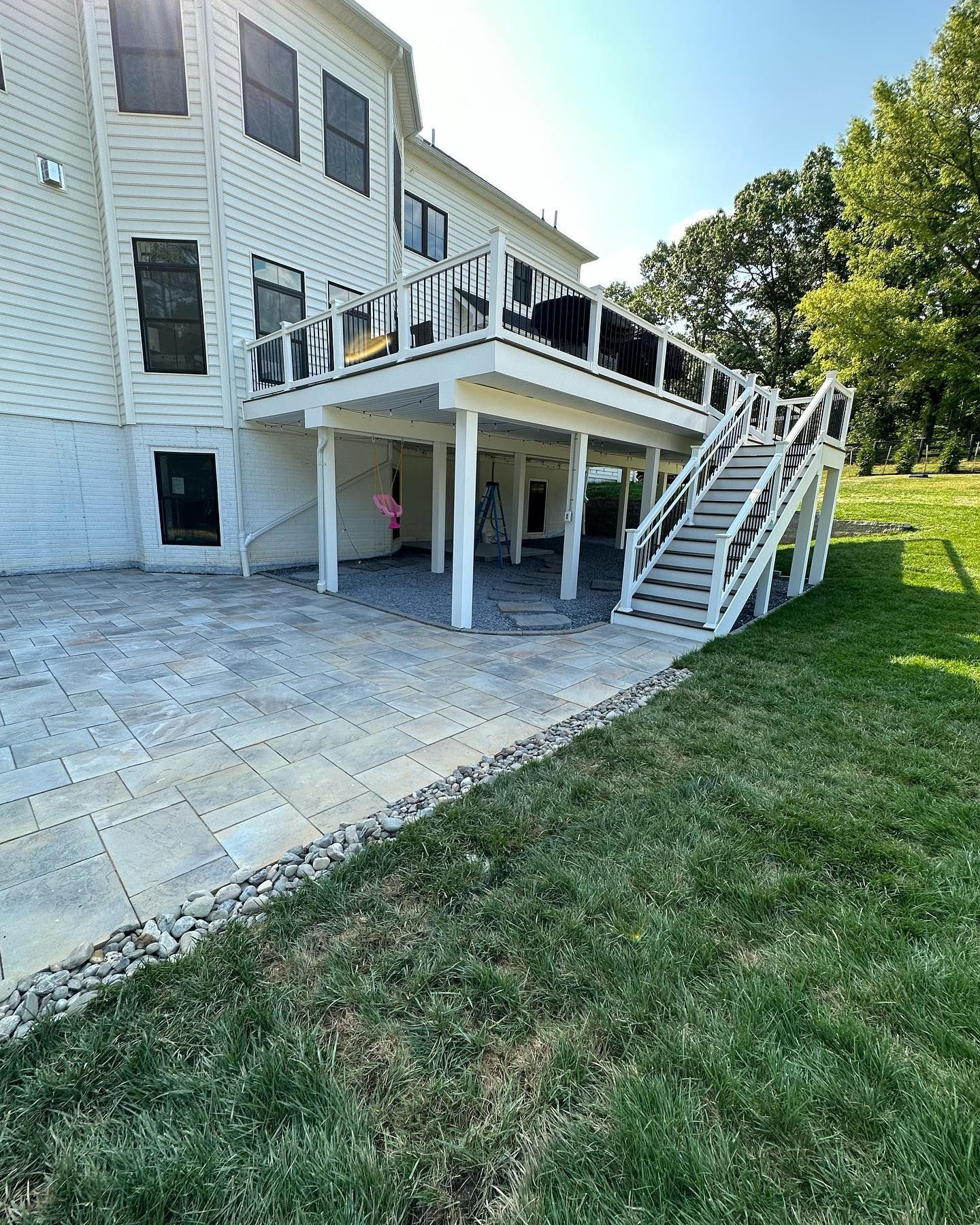 A large white house with a large deck and stairs.