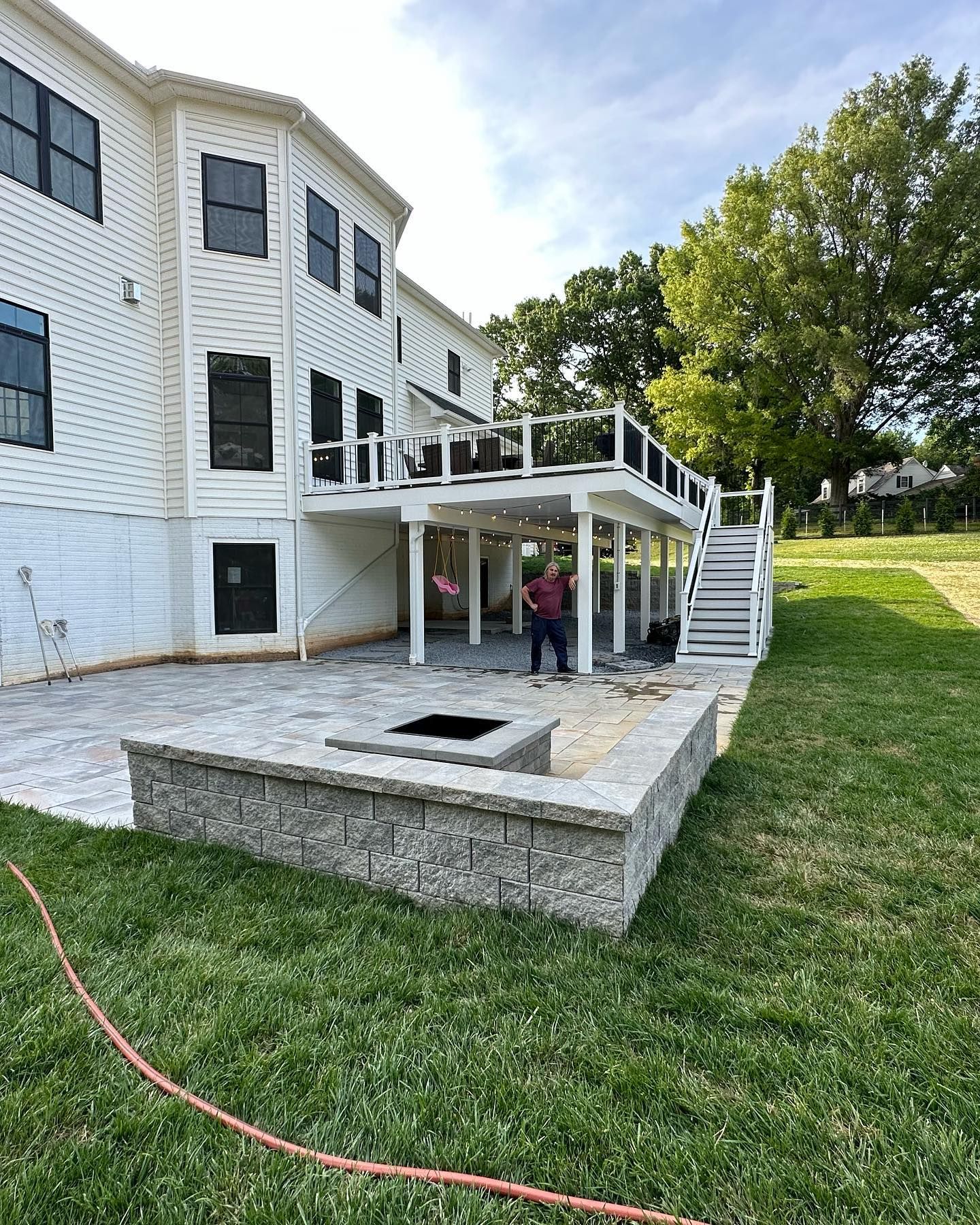 A large white house with a large deck and stairs.