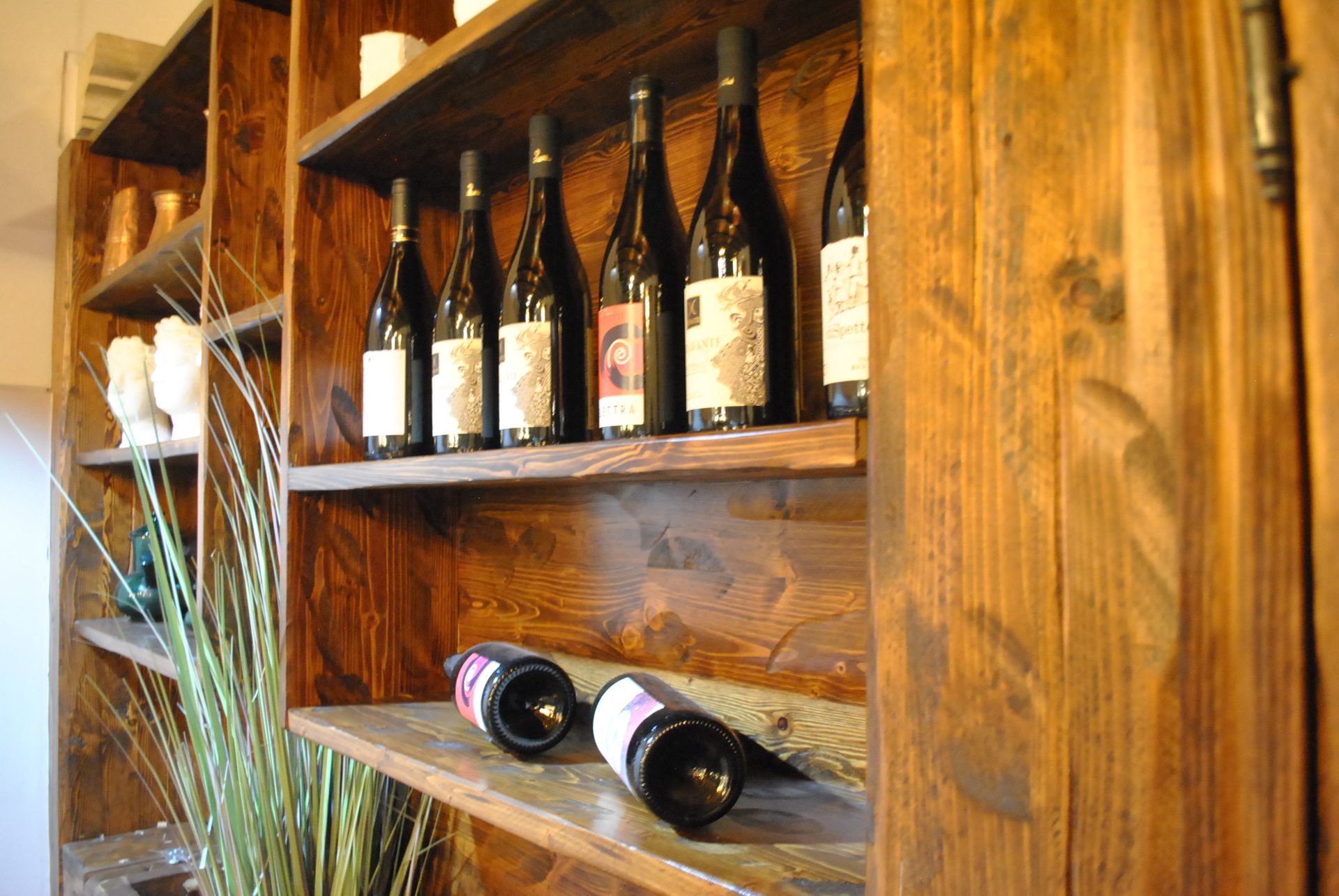 molte bottiglie di vino sono in cima a un scaffale di legno