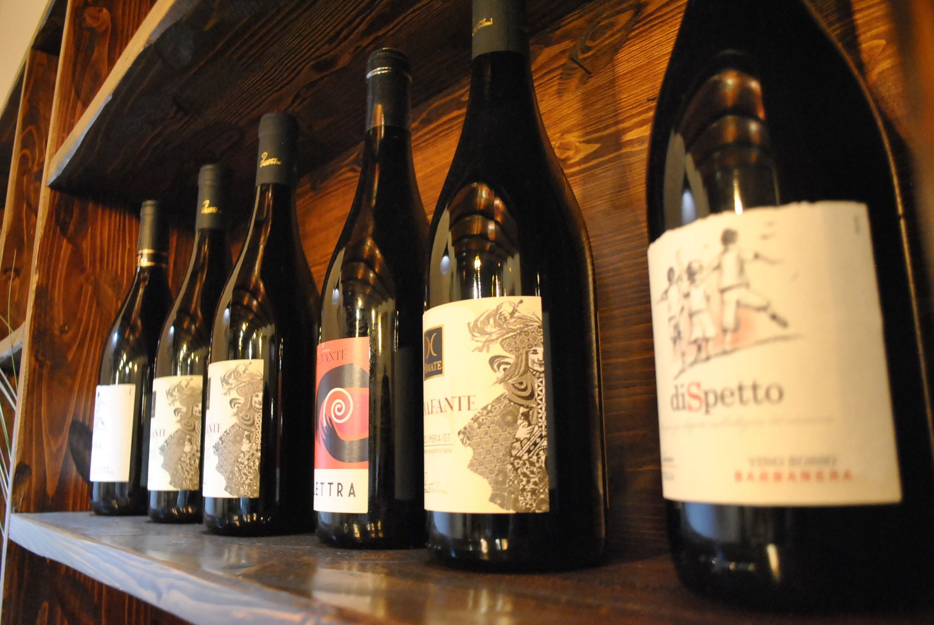 una fila di bottiglie di vino su uno scaffale di legno