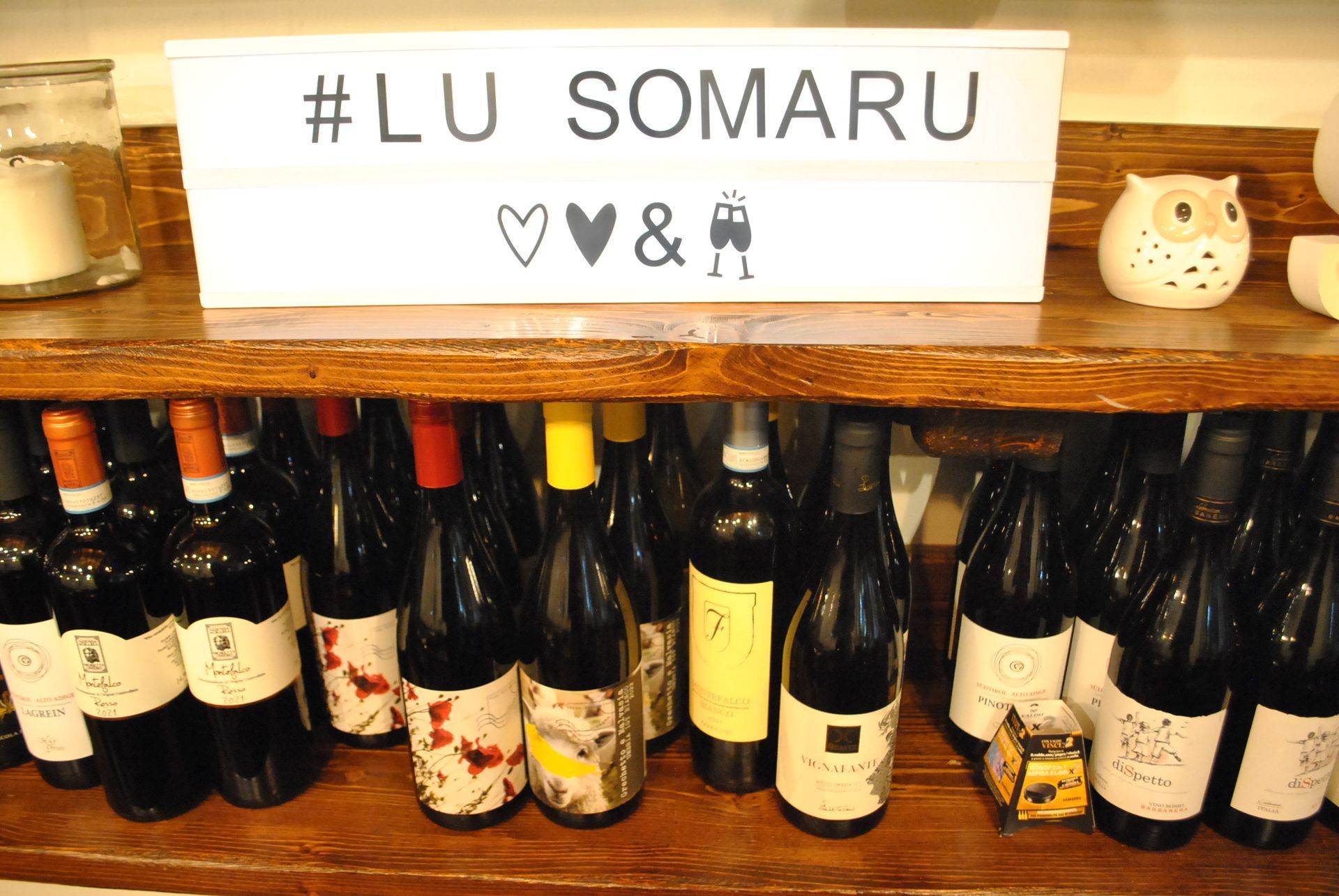 un scaffale pieno di bottiglie di vino e un cartello che dice #lu somaru