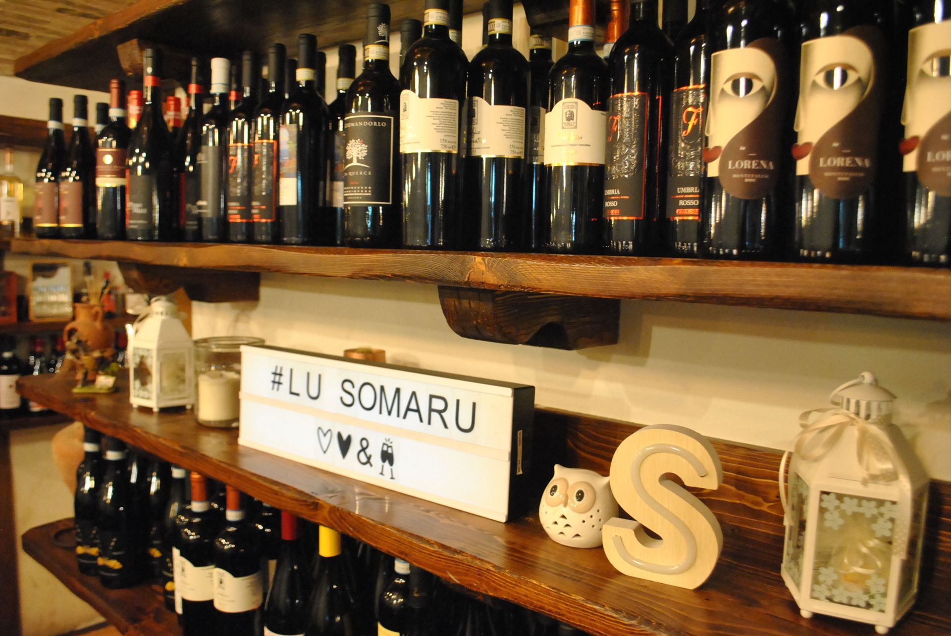 un scaffale pieno di bottiglie di vino e un cartello che dice #lu somaru