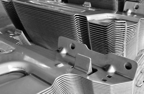 Close-up of stacked metal radiator fins for an industrial cooling unit in grayscale.