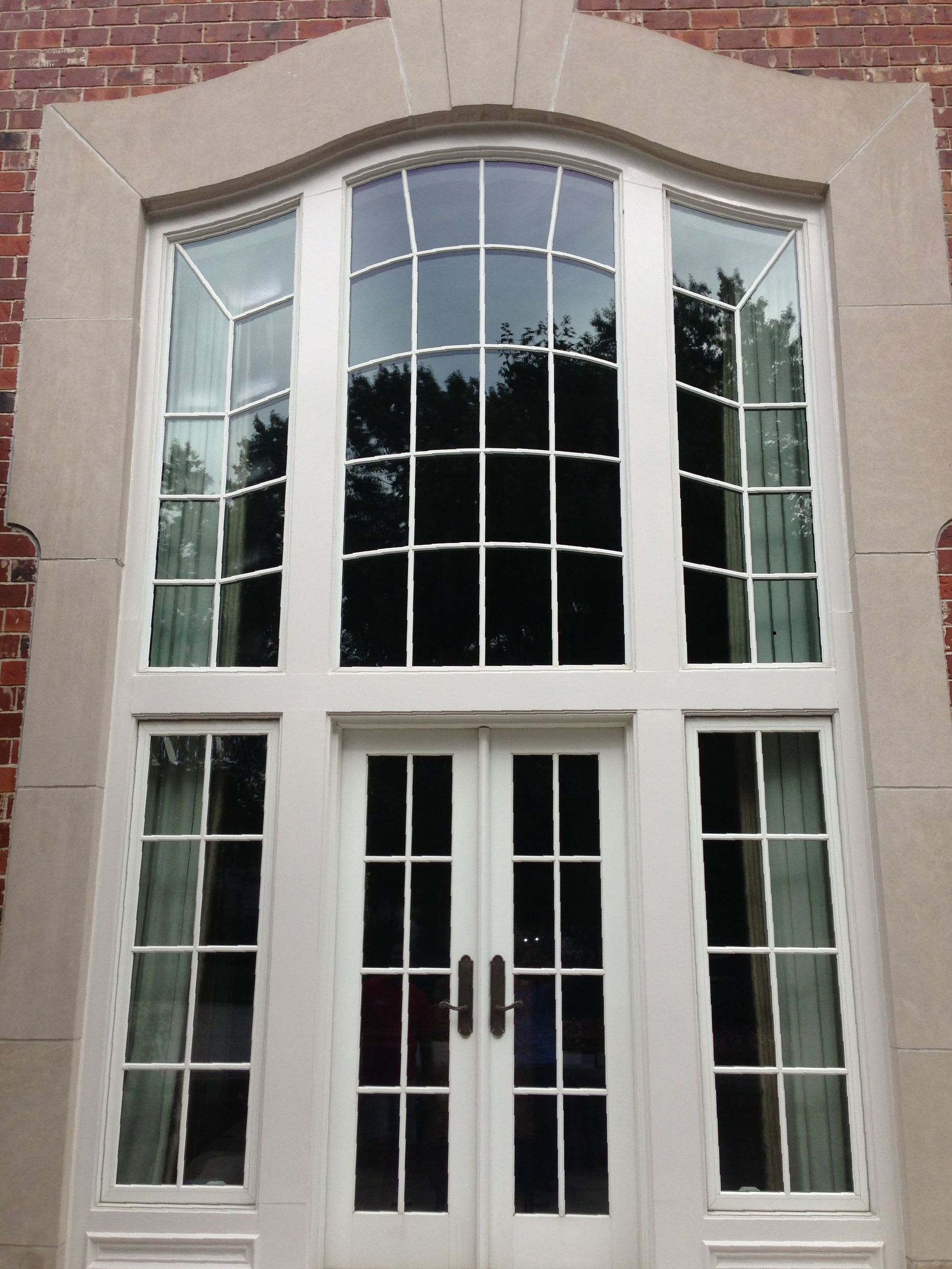 White double doors and arched windows framed by stone and brick.