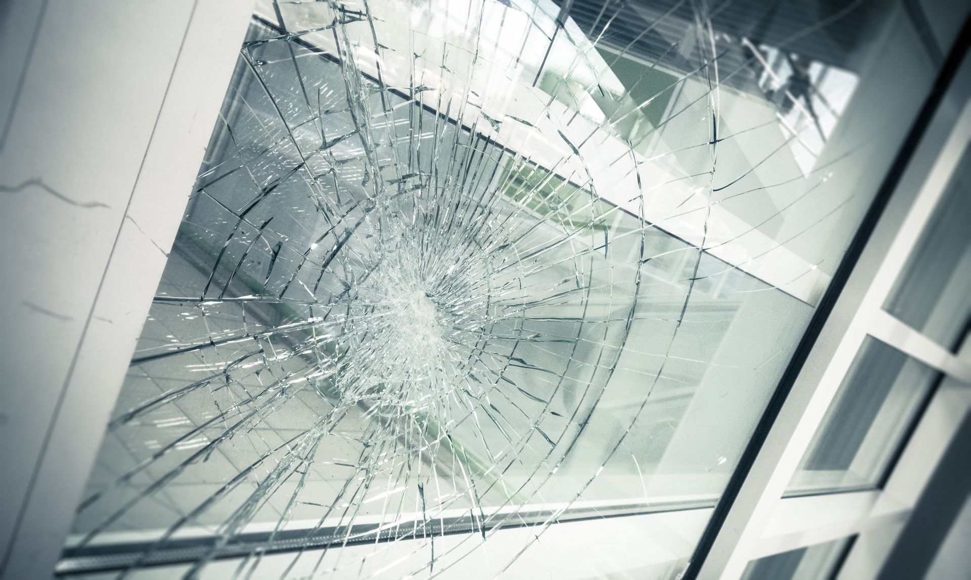 Broken windowpane with radiating cracks; outside view visible.