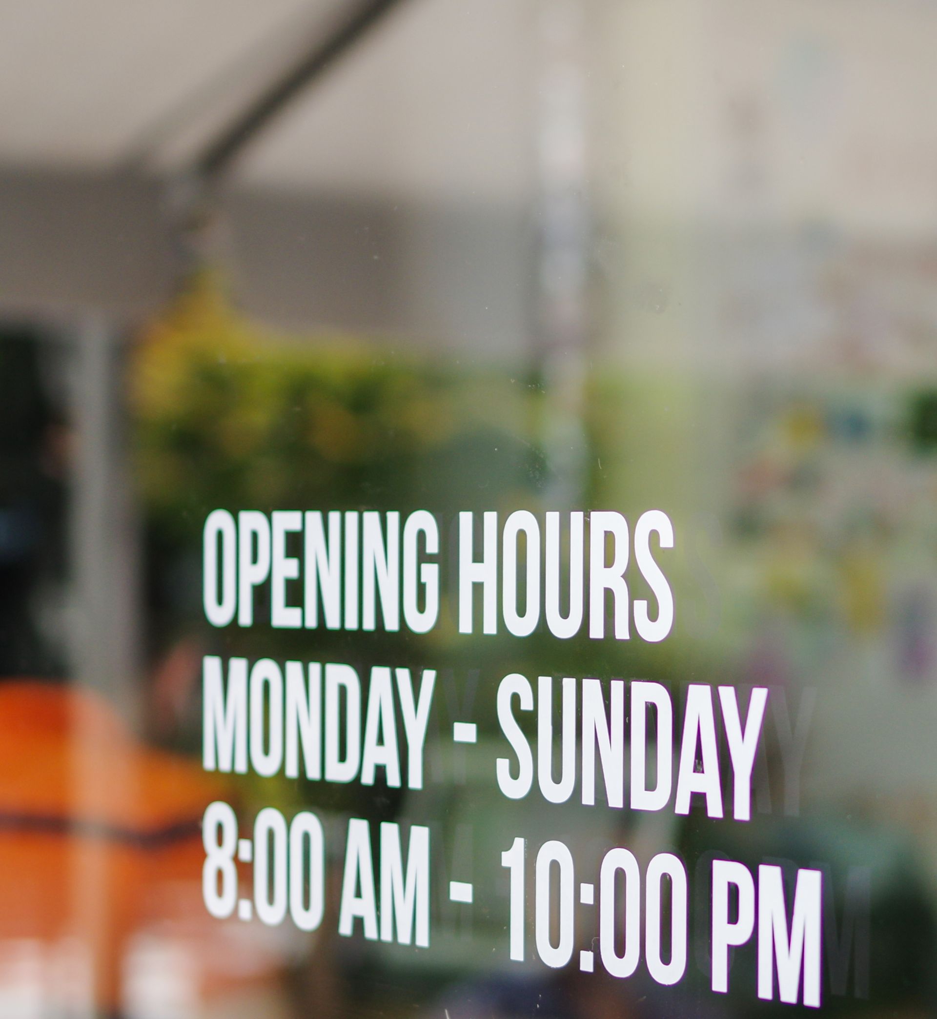 Opening hours sign on a glass door: Open Monday to Sunday from 8:00 AM to 10:00 PM.