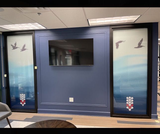 Interior with a navy wall, a mounted TV, and two doors with ocean scene artwork. Birds fly across a gradient blue background.