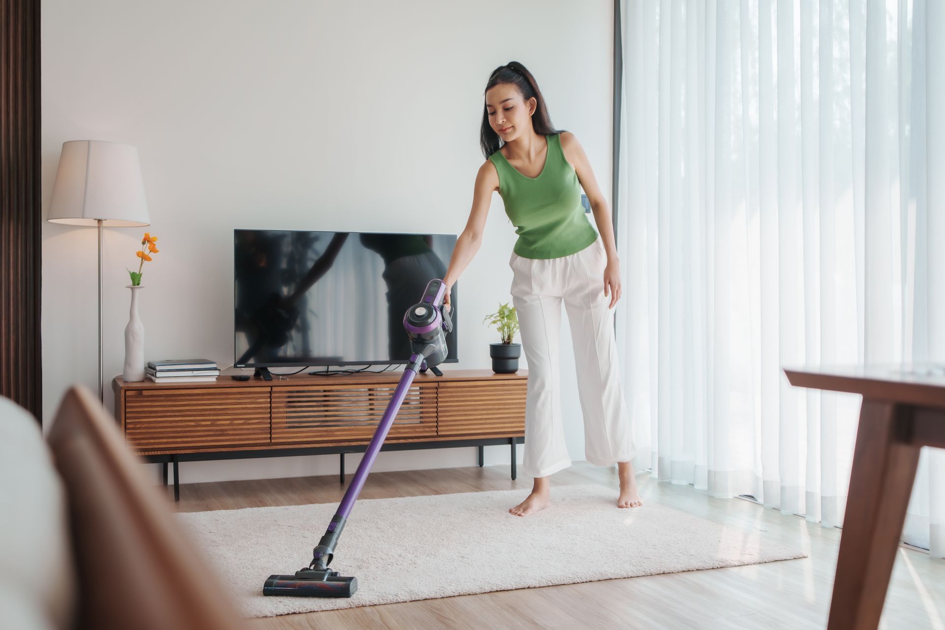 A woman is using a vacuum cleaner in a living room.