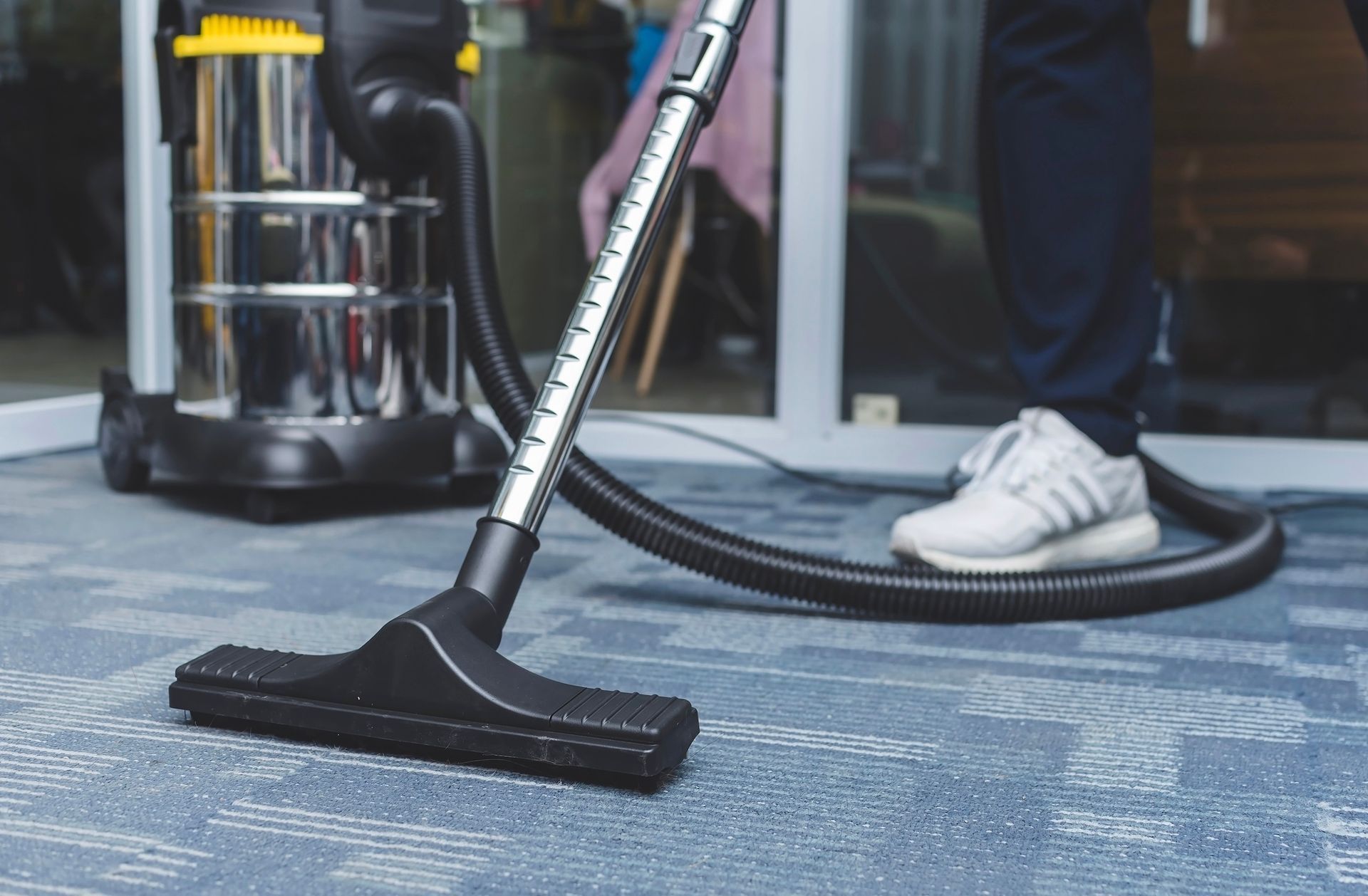 A person is using a vacuum cleaner to clean a carpet.