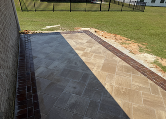 Brick-bordered patio with a stone paver design next to a brick building.