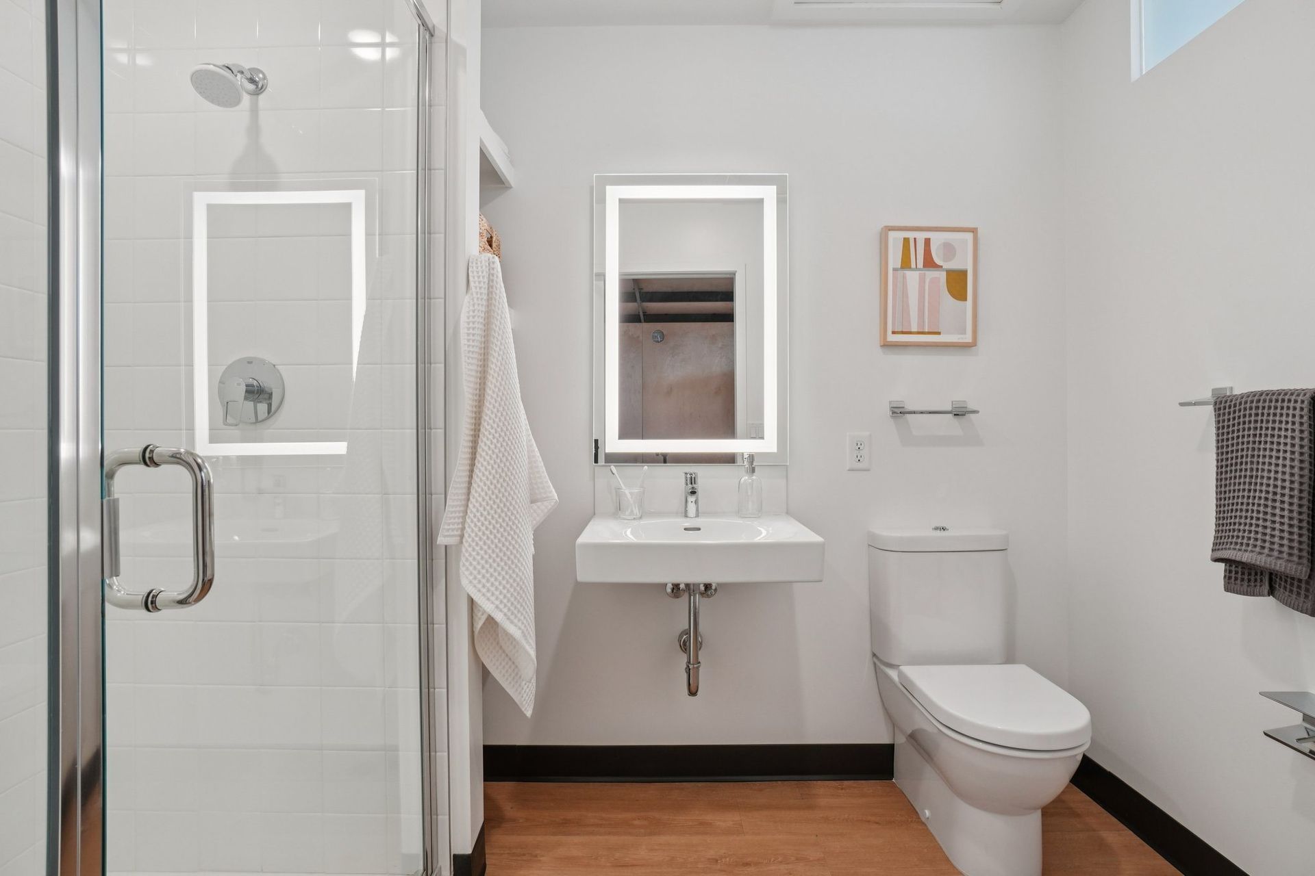A white bathroom with a toilet, sink, and shower.