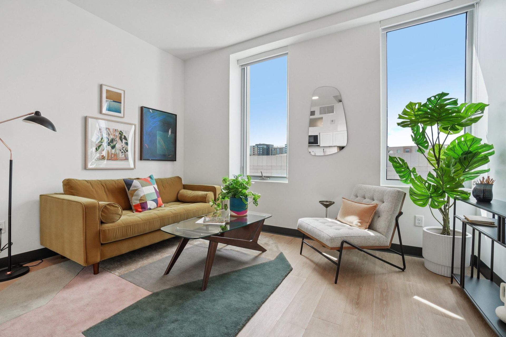A living room with a tan couch, a coffee table, a chair, and a potted plant.