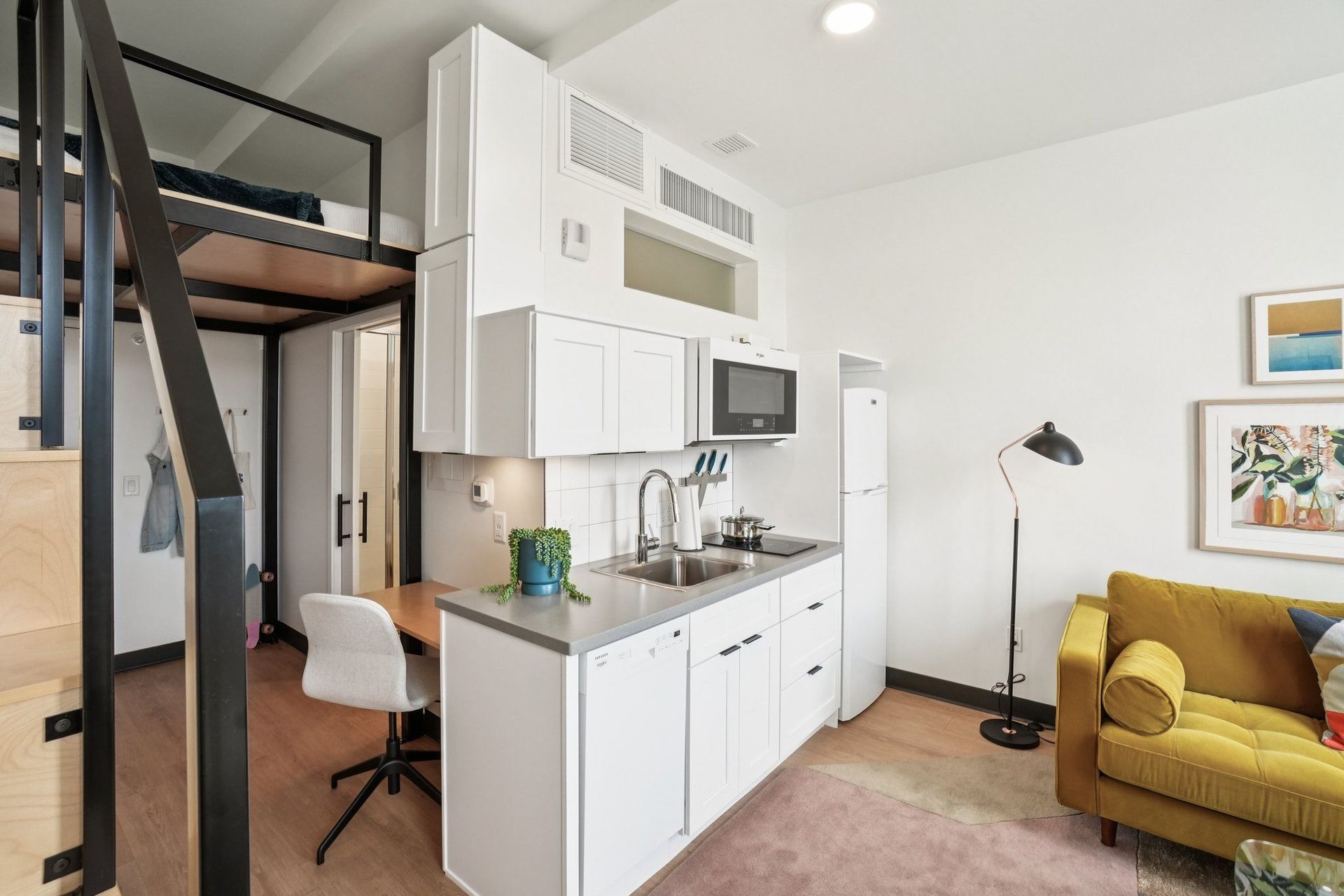 A modern kitchen with white cabinets and a yellow couch.