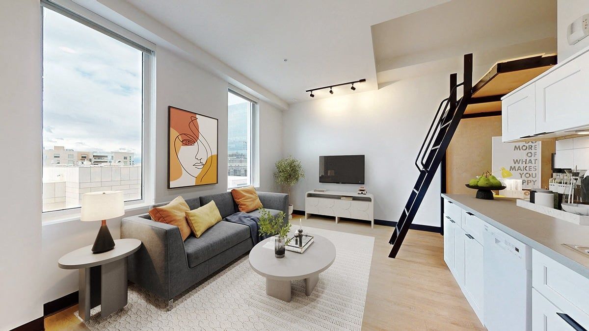 Modern living room with loft, large windows, grey couch, and kitchen area.