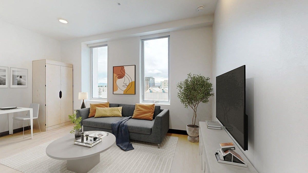 Living room with a gray sofa, TV, and white walls; a round coffee table in front of the sofa.