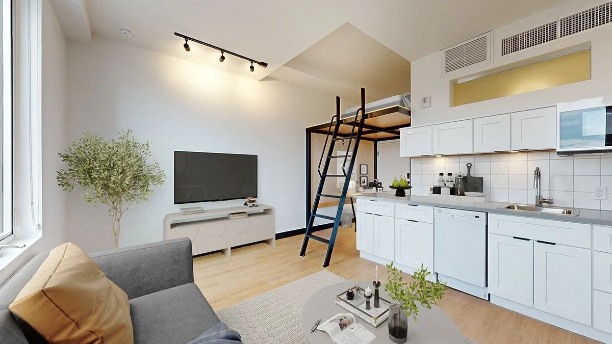Loft apartment with kitchen, living area, and sleeping loft. White walls, wooden floors, and modern furniture.